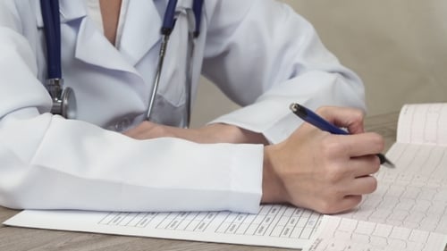 The Doctor Looks Cardiogram And Makes Notes In a Document