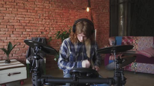 Young Redhead Man Drummer in Headphones Playing Electric Drums at Home Slow Motion