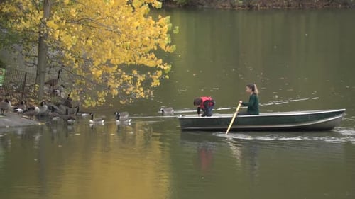 Woman and Child Rowing on Lake in Autumn