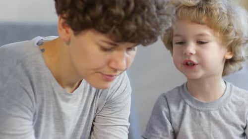 Adorable Kid Speaking with Mom while Making Xmas Paper Crafts