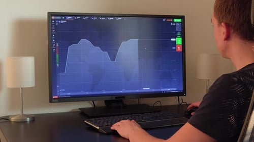 Adult Works at Computer with Stock Chart Displayed