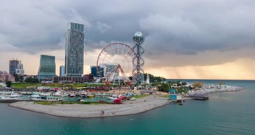 Aerial hyperlapse of Ferris wheel, alphabetic tower, skyscrapers and embankment of Batumi city