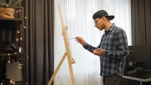 Man Working on Painting on Easel Indoors