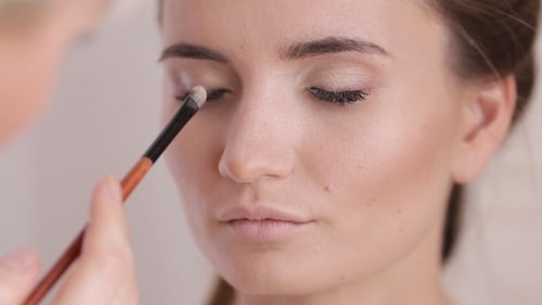 Maskenbildner macht ein Mädchen schön Make-up