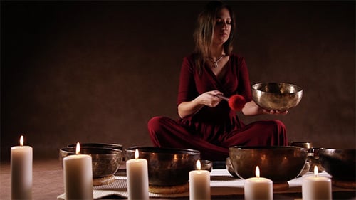 Woman Playing Singing Bowls with Candles