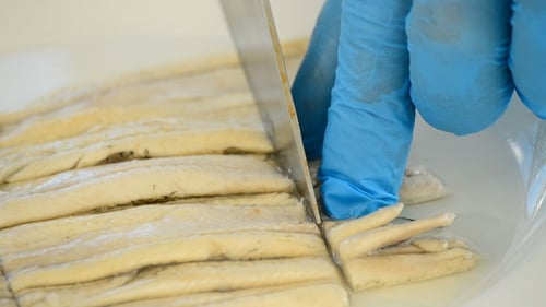 Chef Cuts Marinated Anchovies on White Plate