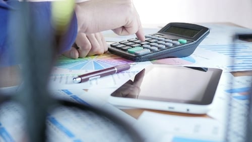 Adult Doing Business Math on Calculator and Tablet