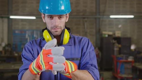 Handsome Worker Puts on Gloves in Workshop