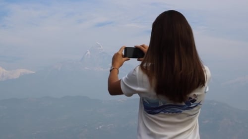 Young Woman Photographs Distant Mountain with Phone
