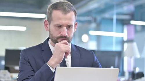 Focused Businessman Working on Laptop in Modern Office