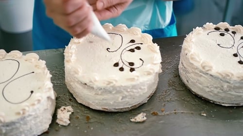 Cakes Being Decorated with Frosting in Bakery