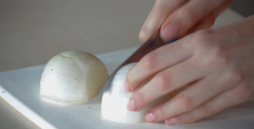Hands Chopping an Onion in Kitchen