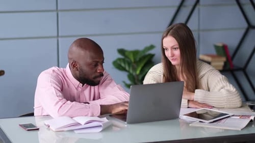 Diverse Business Colleagues Sitting at a Desk in a Modern Office Talking Together Over a Laptop