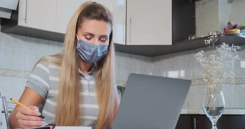 Woman in Gray Mask Works in Laptop