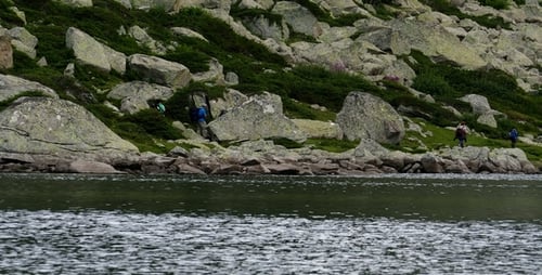 Hikers Traverse Rocky Landscape Near Serene Lake