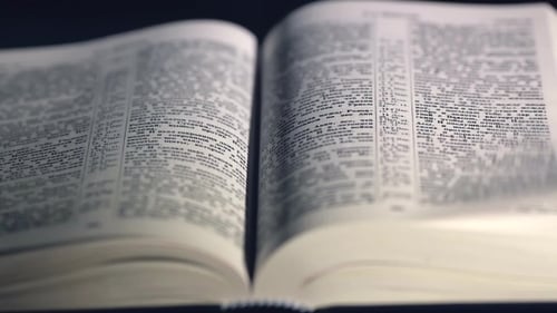 Die Bibel auf schwarzem Hintergrund. Die Seiten der Heiligen Schrift umblättern.
