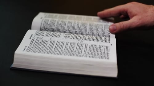 Die Bibel auf schwarzem Hintergrund. Die Seiten der Heiligen Schrift umblättern.
