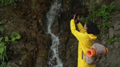 Woman Tourist is Filming Small Waterfall in Forest By Camera of Smartphone
