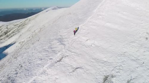 Hikers Walking Along Snowy Mountain Ridge in Winter
