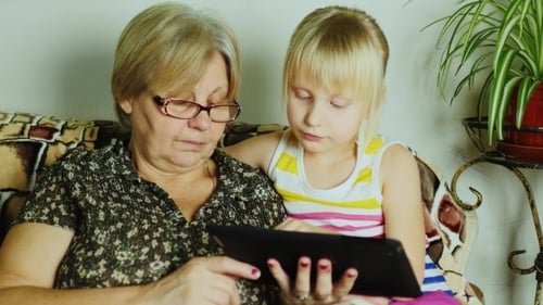 Child and Adult Enjoying Tablet Together Indoors