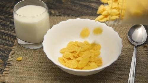 Crispy Cornflakes Pouring into Bowl with Milk