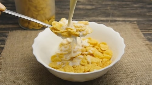 Milk Pouring Over Cornflakes in Bowl Close Up