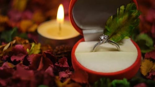 Engagement Ring in Box with Burning Candle and Petals