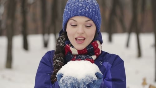 Woman Blowing Snow in Winter Wonderland