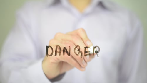 Man Writing Danger with Black Marker on Glass