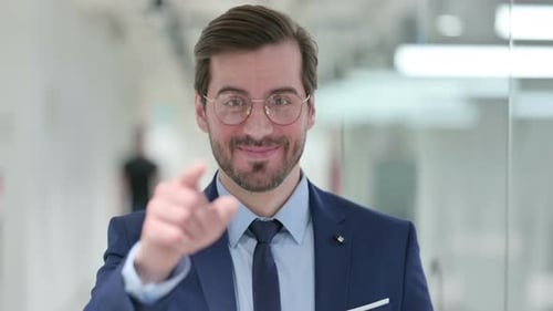 Portrait of Assertive Young Businessman Pointing with Finger and Inviting