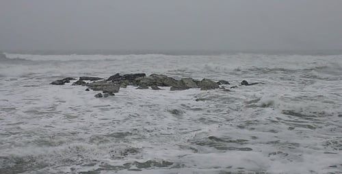 Waves Crashing on Rocky Shoreline in Overcast Weather