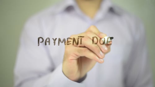 Hand Writes Payment Due on Clear Surface