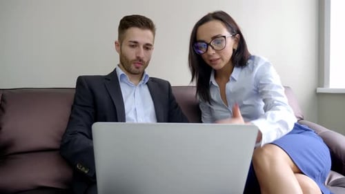 Colleagues Collaborate Using Laptop in Office Setting