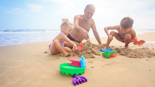 Grandpa Kids Build Sand Castle on Beach by Wave Surf