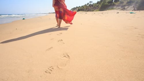Woman Walks on Sandy Beach During the Day