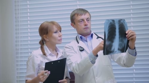 Two Doctors Examining Patients X-rays In Hospital