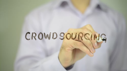 Man Writes Crowdsourcing on Clear Surface