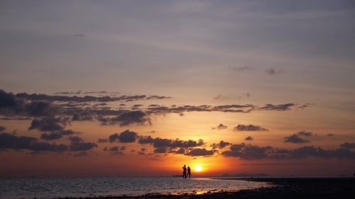 Silhouette Of Happy Couple On Summer Beach At Sunset