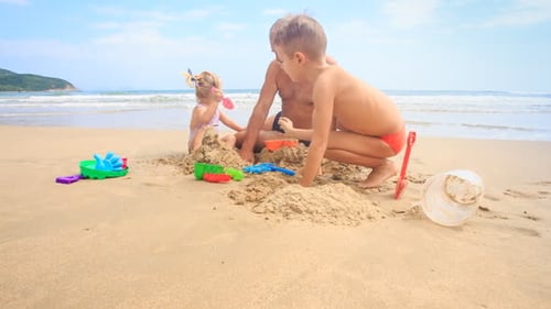 Niños del abuelo construyen un castillo de arena en la playa con Wave Surf