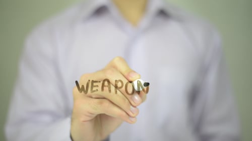Hand Writes the Word Weapon with a Marker