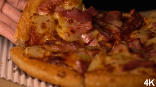 Hand Taking Slice of Pizza With Bacon and Pineapple