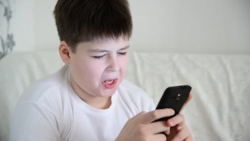 Boy Using Phone Smiling Indoors