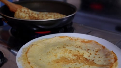 Stack of Golden Crepes Being Cooked at Home