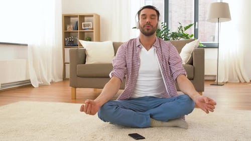 Man in Headphones Meditating in Lotus Pose at Home 69