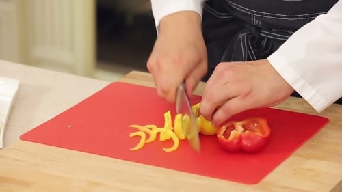 Chef Slicing Colorful Bell Peppers in Kitchen