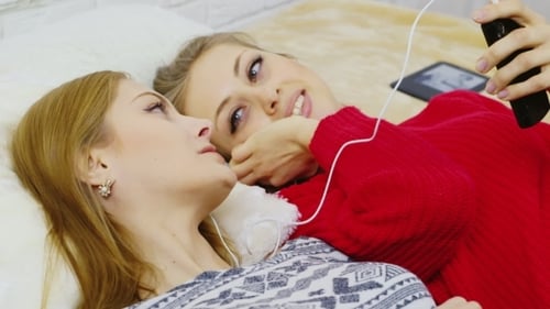 Women Listen to Music Together on Bed