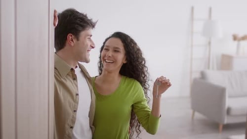 Happy Wife Showing Key To Husband Standing In New Home