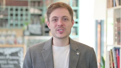 Young Adult Man Talking and Waving Indoors