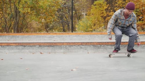 Skater Practicing in the Autumn Concrete Skate Park Making Tricks and Rides in Ramp