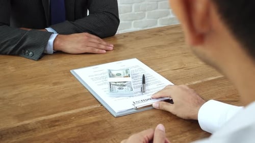 Businessman offering bribe money together with contract agreement paper